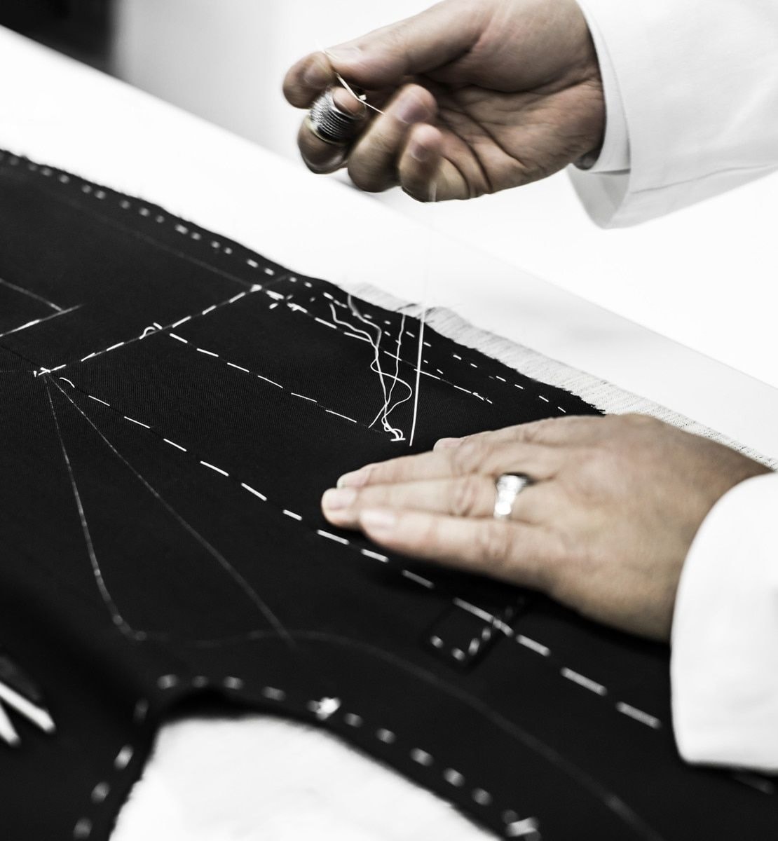 Nahaufnahme von Händen bei der präzisen Arbeit mit Stoff — Metapher für Maßarbeit